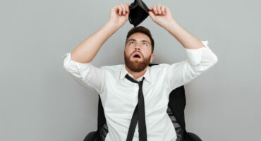 Frustrated surprised bearded man in white shirt showing empty wallet