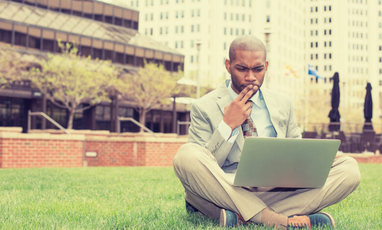 business man sitting outside corporate office working on compute