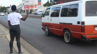 A commuter signals a mini bus taxi to stop for her.