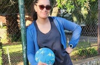 Maria Singh posing next to a netball hoop