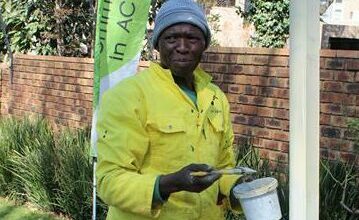 Vusi Xaba paints a road sign pole.
