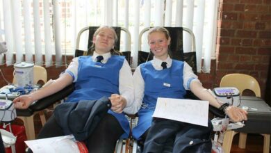 Devanie Lutz and Isabelle Roberts hold hands while they donate blood. Photo: Asanda Matlhare