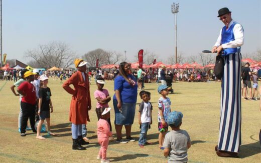 Children and parents alike enjoy some goodies from the stilt walker. Photo: Naidine Sibanda