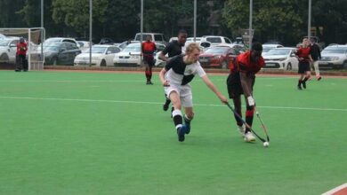A Jeppe High School for Boys team member (black and white) tackles the ball from Parktown Boys' High School player in red and black. Photo: Naidine Sibanda
