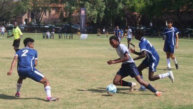A St Albans player in grey and navy blue kicks the ball with all his might as St Stithians players in blue stand in defence. Photo: Naidine Sibanda