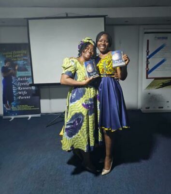 Author Victorine Mbong Shu and Beatrice Bih Sabum hold copies of Not Too Late: Bring Back Involved Parenting.