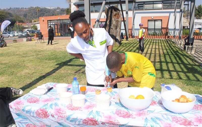 Founder of Positive Pageantry Linda Shezi helps Sfiso Zuke in decorating his own cupcake at their cupcake station on July 25, 2026. Photo: Thato Modopi