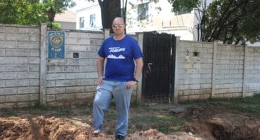 Ward 72 councilor Daniel Schay stands in between the dangerous excavations on Club Street on September 28, 2026. Photo: Asanda Matlhare