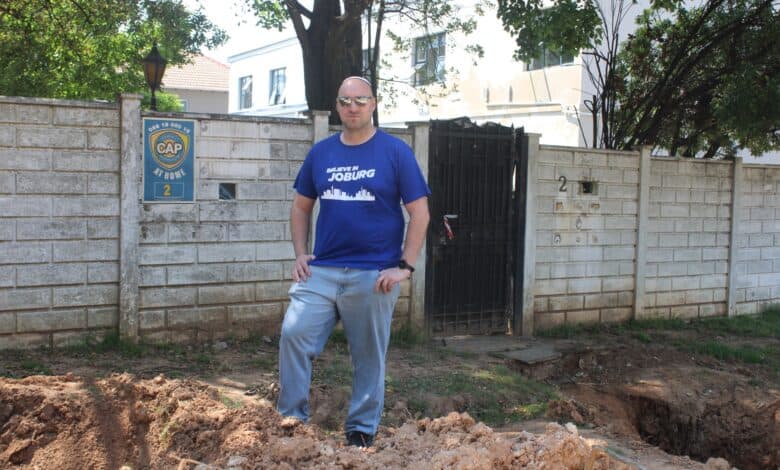 Ward 72 councilor Daniel Schay stands in between the dangerous excavations on Club Street on September 28, 2026. Photo: Asanda Matlhare