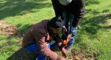 At Zoo Lake on October 1, 2026, a private electrician crouches over the exposed cable while a colleague holds a phone and a testing device beside him. They are checking whether the wires are still live. Photo: Naziya Davids-Easthorpe