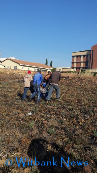 Employees from Magic Pluming carried the suspect out of the field where he was caught on Tuesday, May 19 after stealing a woman’s handbag. 