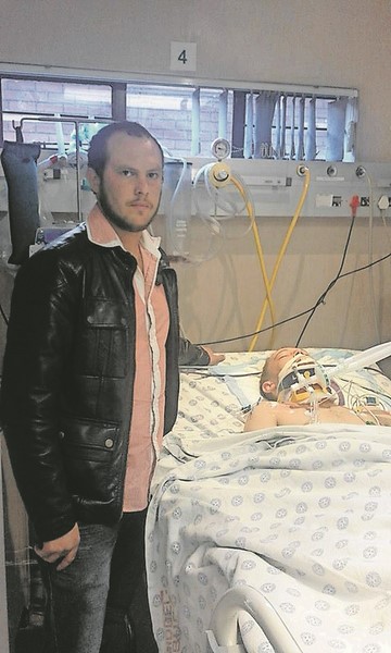Mnr. Jean-Paul Booyens staan langs sy broer mnr. Domonic Booyen’s se bed in Witbank Hospitaal, Dinsdag 21 Julie.