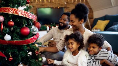 Happy African American family decorating Christmas tree at home.
