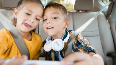 Children with headphones and toy taking selfie on smartphone in car, banner