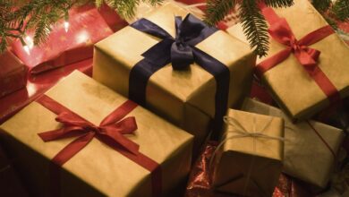 Christmas presents piled underneath a christmas tree.