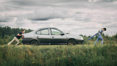 Couple pushing their broken car down the country road