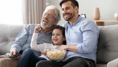 Happy three generation men family hold remote control watch tv