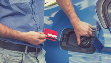 Man with credit card opening fuel tank of his new car