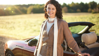 Portrait of woman standing next to convertible car.
