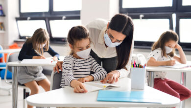 Teacher and children with face mask back at school after covid-19 quarantine and lockdown.