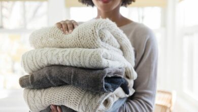 Woman holding stack of folded sweaters