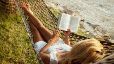 Woman lying in a hammock on the beach and enjoying a book reading