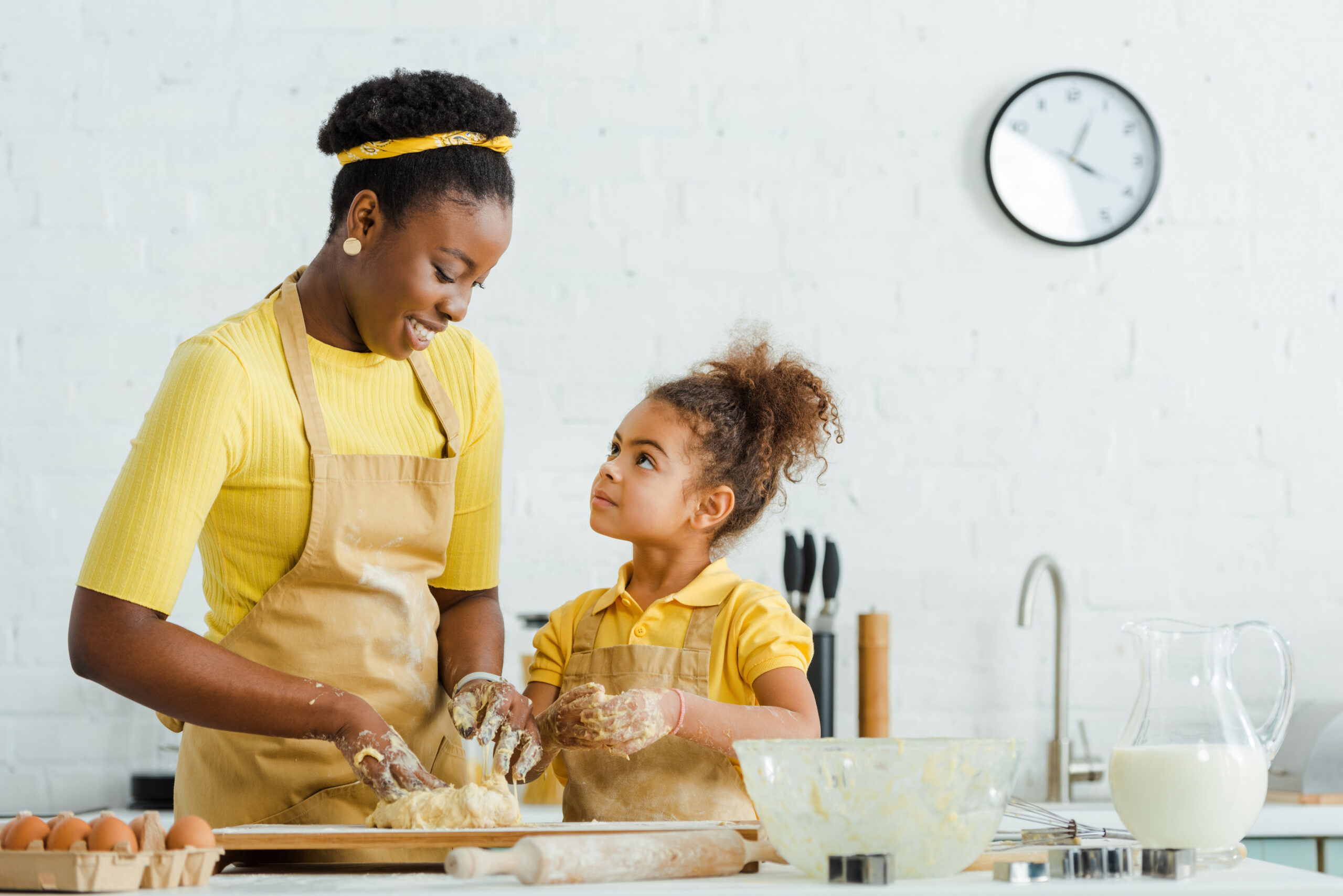 cute african american daughter looking at cheerful mother kneadi