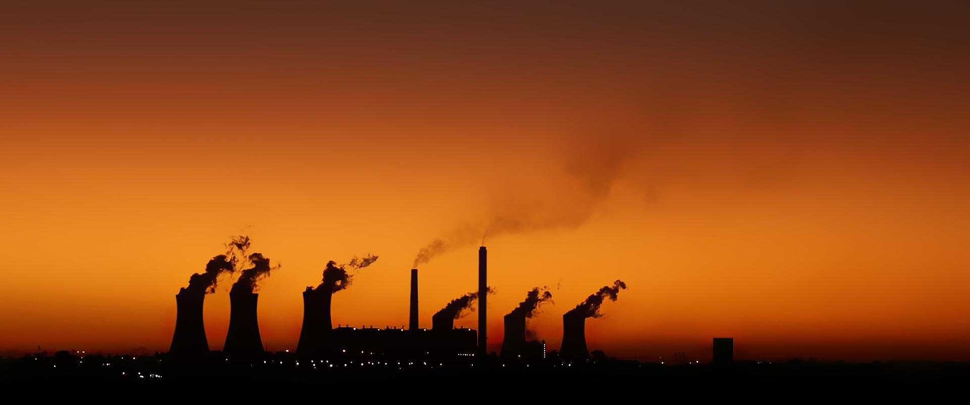 Silhouette of Matla Power Station against an orange sky at sunset.