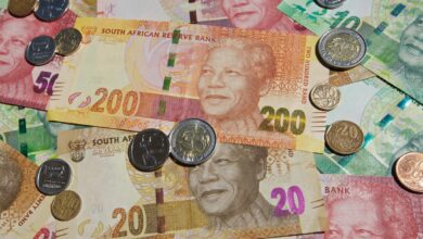 South African rand banknotes and coins scattered, symbolising financial news and currency exchange.