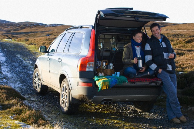 Couple enjoying picnic in back of car on remote road