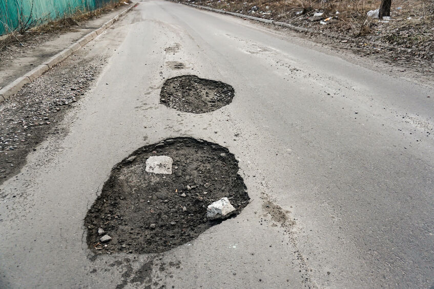 large pit with stones on the asphalt highway