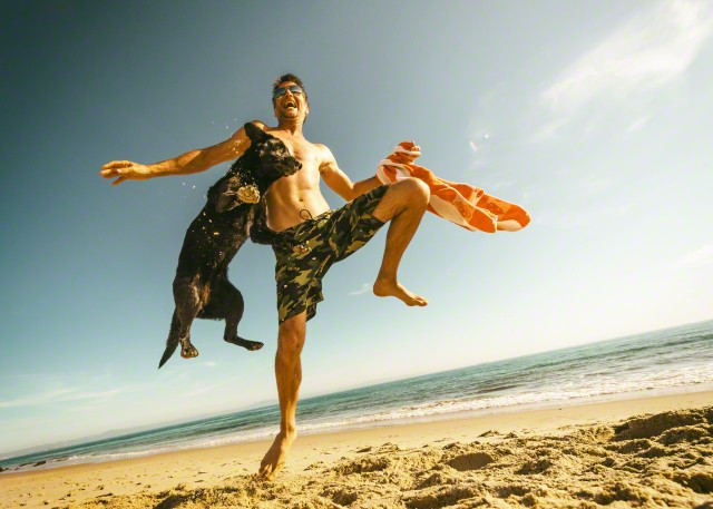 Man and pet dog having fun at the beach.
