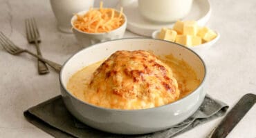 Whole baked cauliflower smothered in a creamy cheese sauce