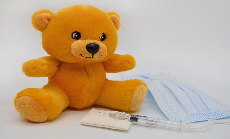 Tan teddy bear with a syringe and medical mask
