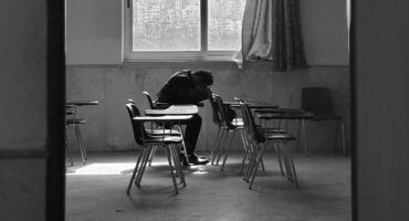 Man lying on his arms on a school desk