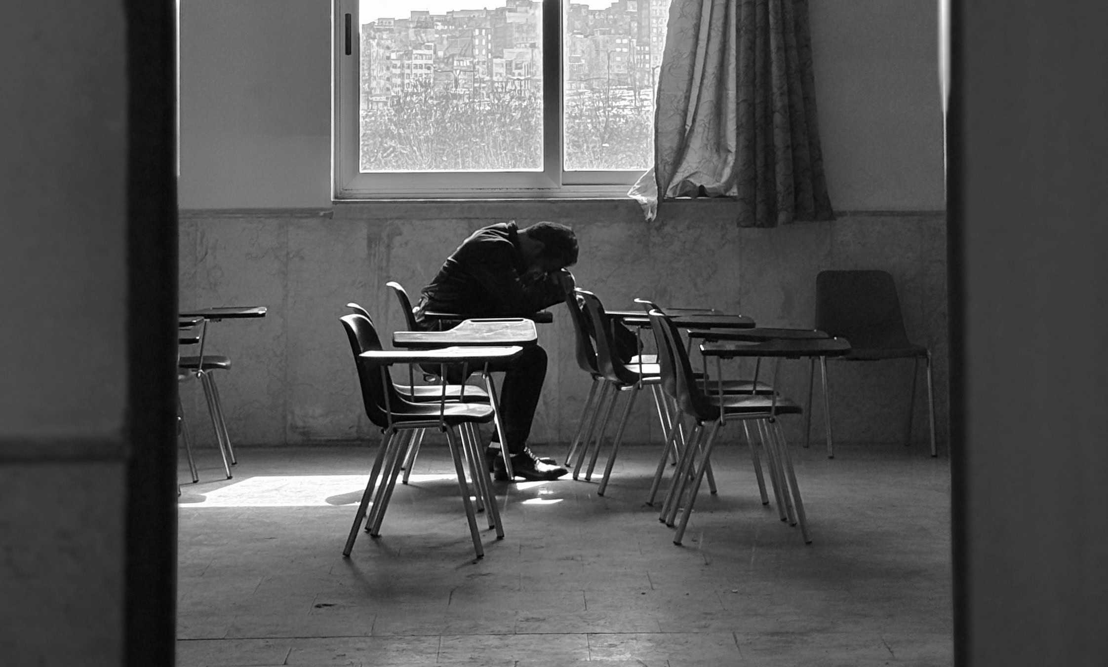 Man lying on his arms on a school desk