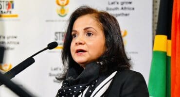 Shamila Batohi speaking into a microphone. In the background government branding is visible.