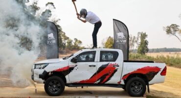 Man with a hammer wearing a helmet standing on the roof of a Toyota Hilux double cab bakkie