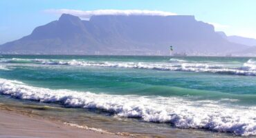 Table Mountain in the background with waves crashing on a beach in the front