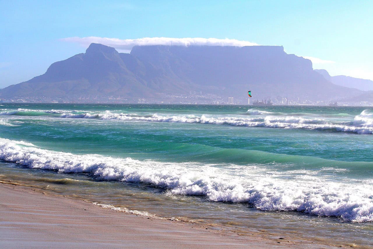 Table Mountain in the background with waves crashing on a beach in the front