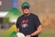Springboks coach Rassie Erasmus wearing a green hat, a black T-shirt, carrying a rugby ball in his hand.