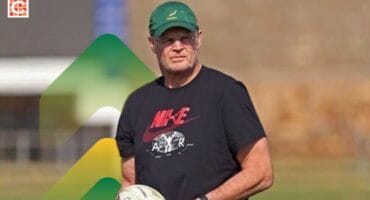 Springboks coach Rassie Erasmus wearing a green hat, a black T-shirt, carrying a rugby ball in his hand.
