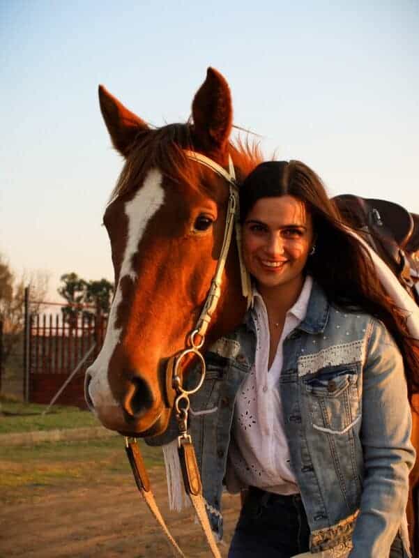 Woman with long dark hair standing next to a horse