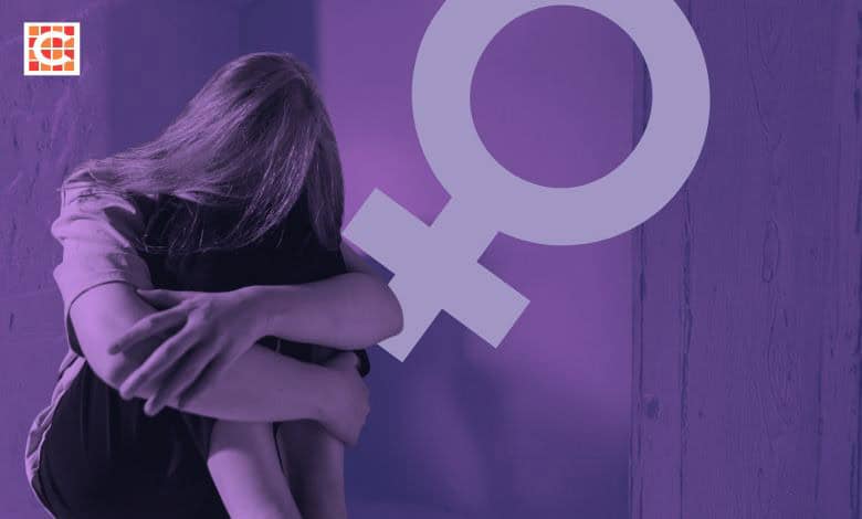 A solitary person sits curled up in a corner with head hidden by hair. A large female gender symbol overlays the image, conveying a sense of vulnerability.
