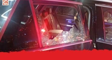 A luxury black vehicle with broken backseat window.