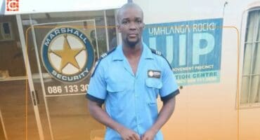 The security guard, dressed in a blue uniform, standing outside the Marshall Security offices.