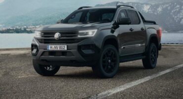 Dark VW Amarok viewed from front and side parked on tarmac.
