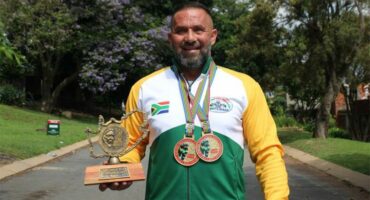 Athlete in Springbok colours showing off a trophy with two medals hanging around his neck