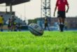 A rugby ball set up for a kick with a referee walking towards it in the background.