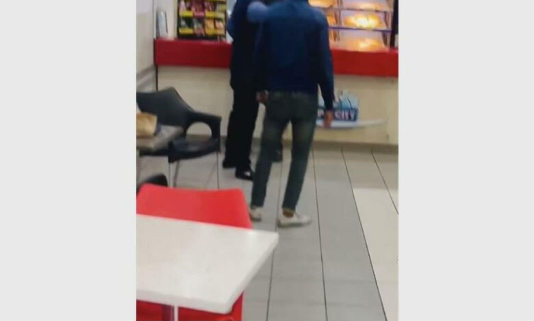 A security guard protects the man from an angry mob.